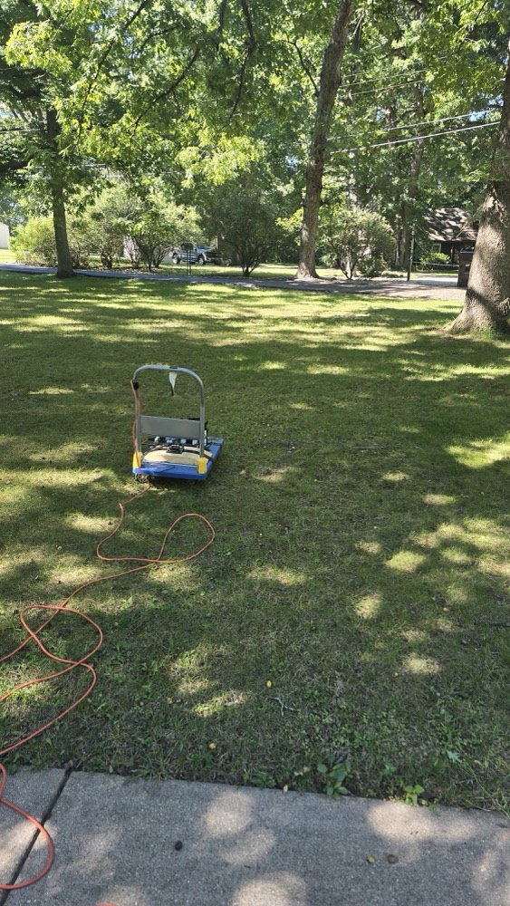 The hand cart with cameras and a Jetson on a lawn, extension cord trailing, road and trees beyond.